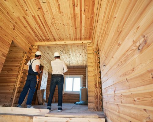 Two people with backs turned to camera looking at house room and discussing next steps in building