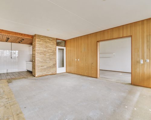 Empty room with wooden walls and a place for the kitchen