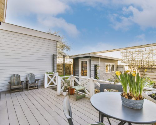 Neat paved patio with sitting area and small garden near wooden fence
