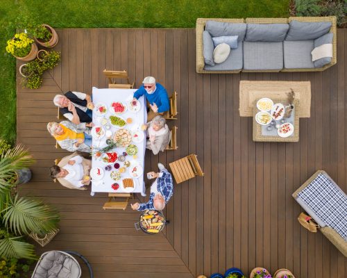 Group of senior friends sitting by the table on a terrace in the backyard
