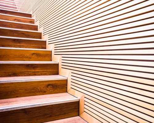Steps on a ladder next to a wall of wooden boards in sustainable construction.